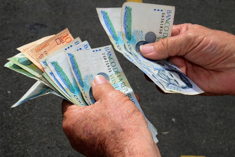 Homem contando os pesos colombianos
