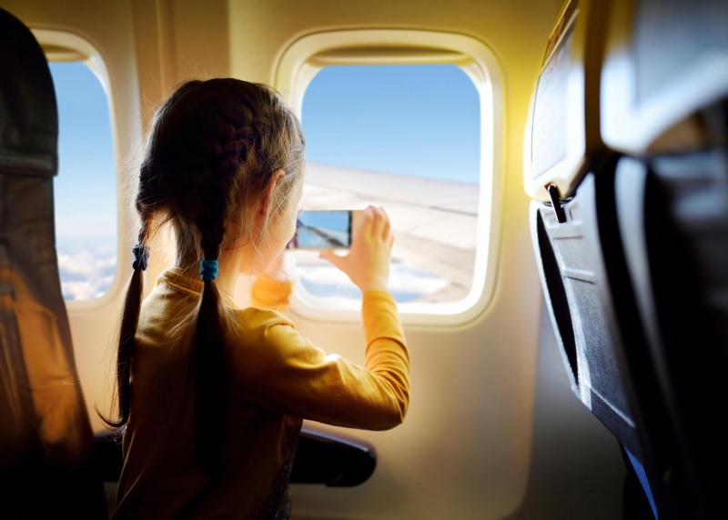 Criança olhando pela janela do avião